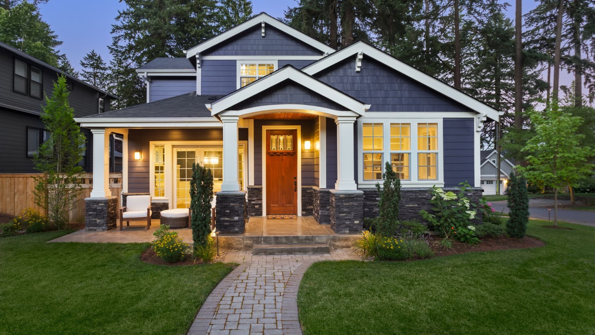 Modern two-story craftsman home with glowing windows and stone accents