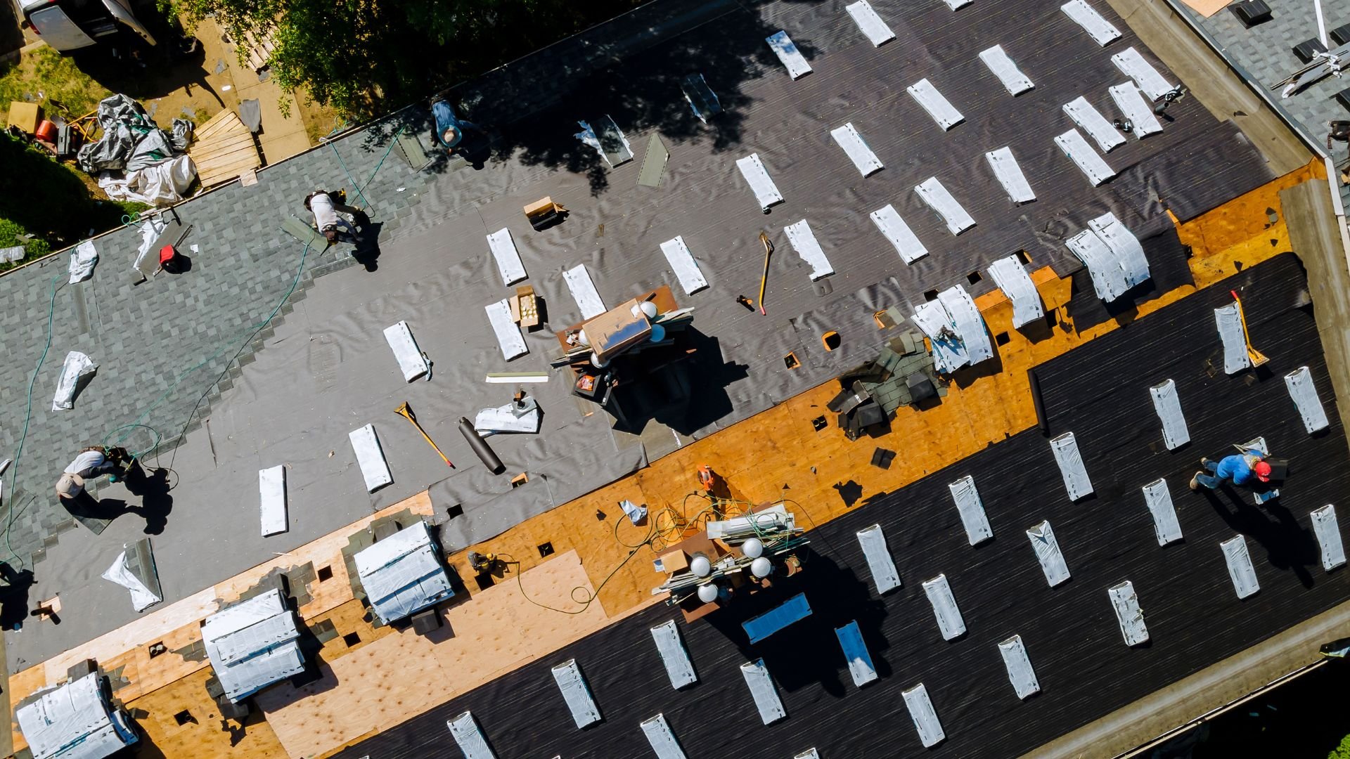 Aerial view of workers installing roofing materials on a large building