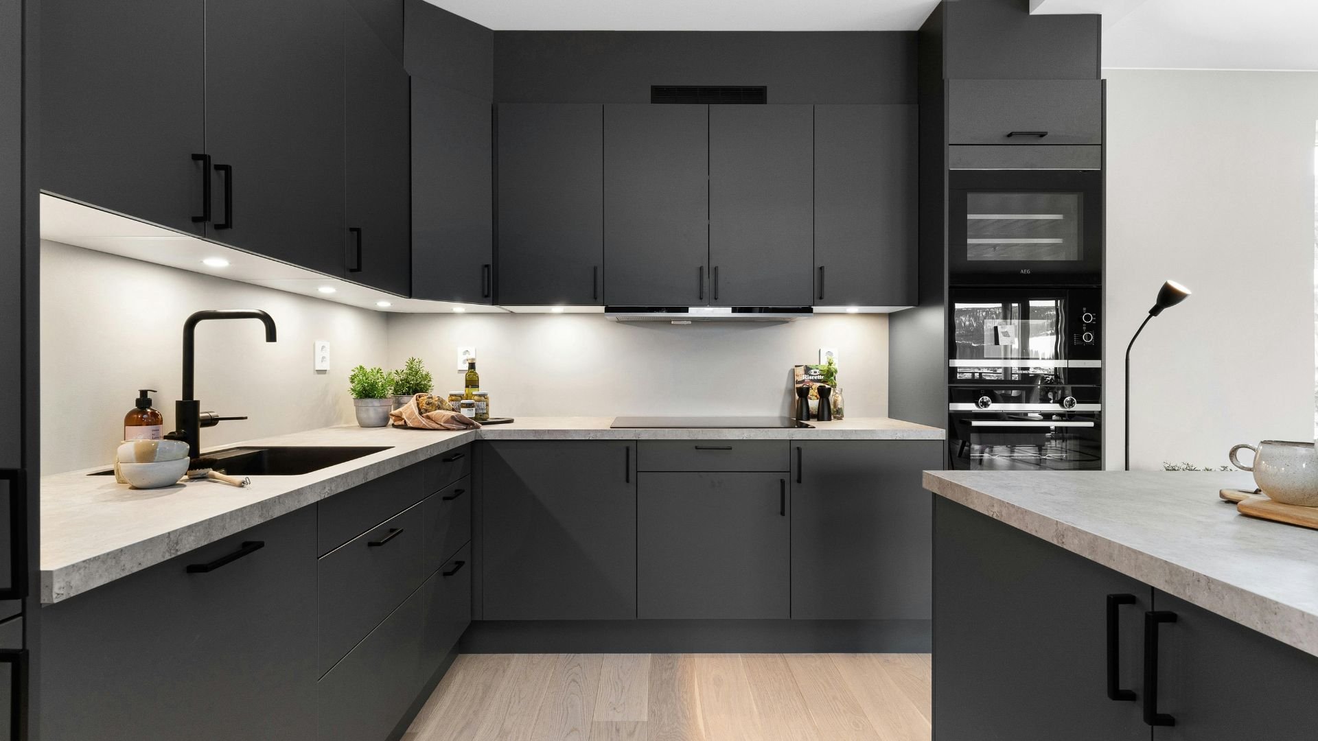 Modern dark gray kitchen with white countertops and built-in appliances