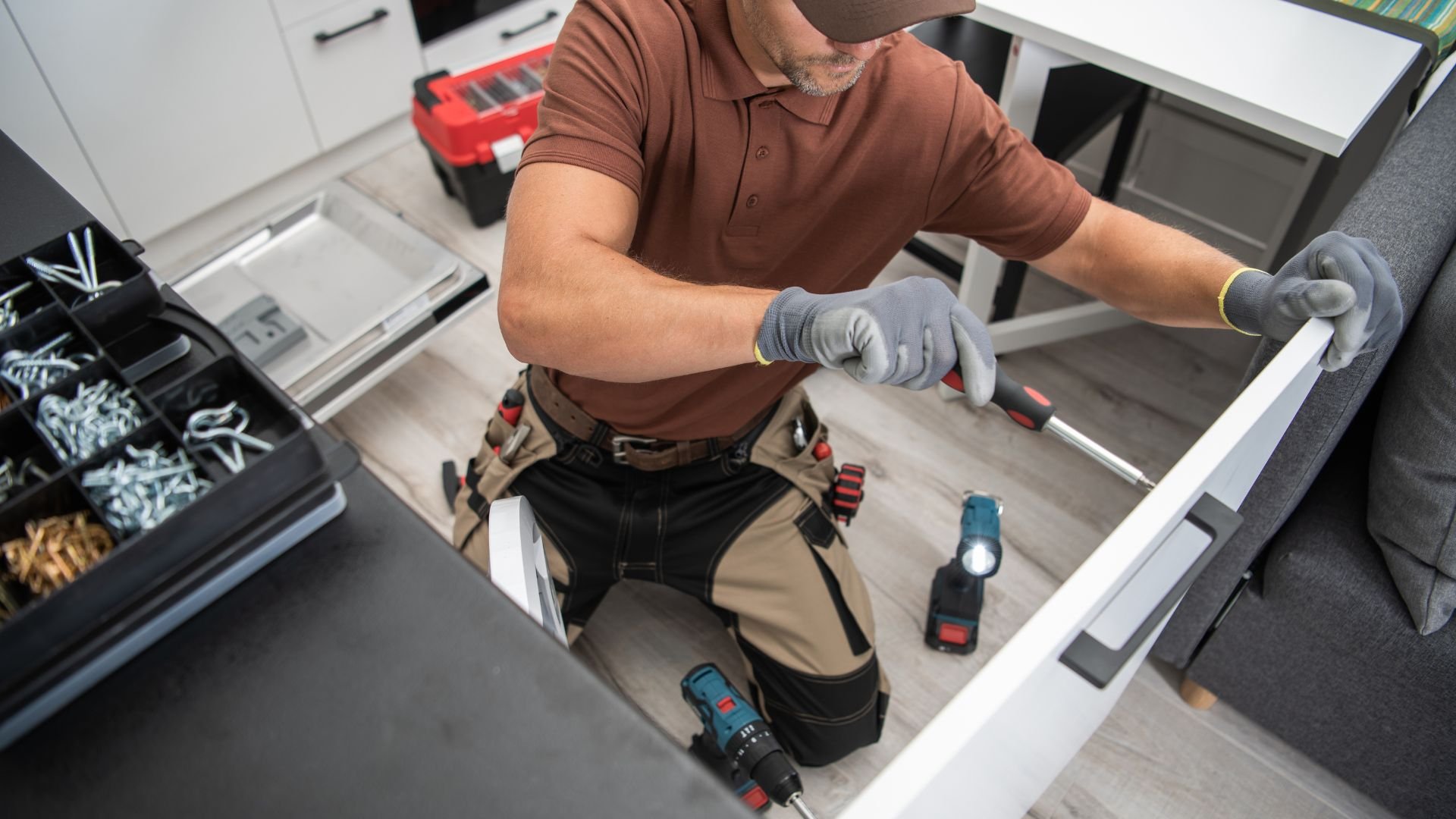Worker installing drawer with tools and utility belt in workshop